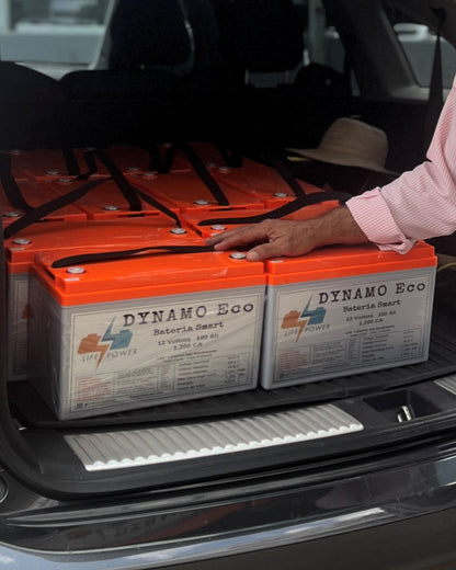 Baterías DYNAMO ECO 12V 100Ah 1,200 CA en la maleta de una SUV, con una mano para ver el tamaño